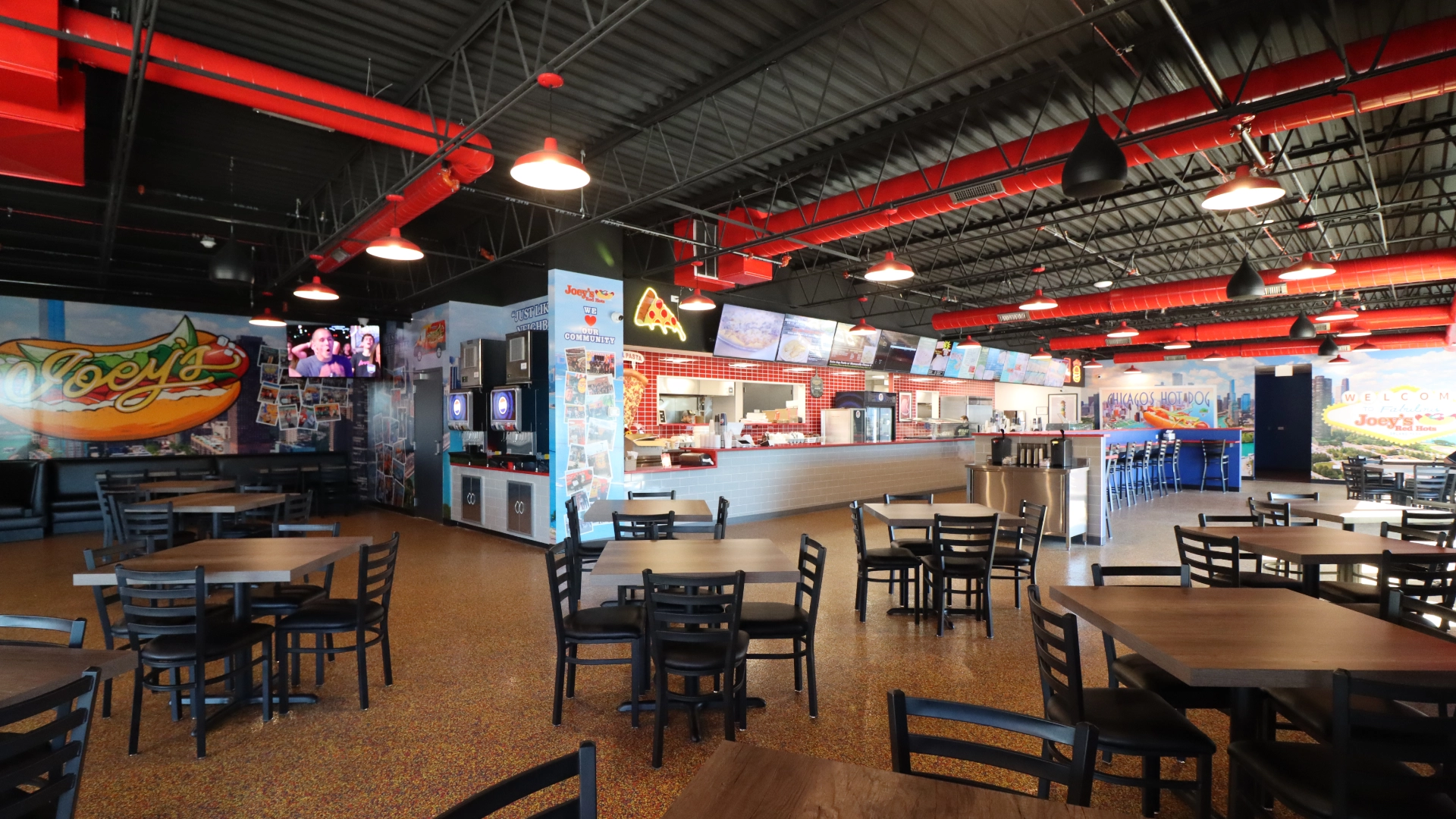 Large dining room inside the new Joey's Red Hots location in Orland Park with tables, murals and service counter